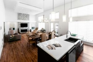 A bright kitchen with an island opens toward a dining room while a partial wall provides separation.